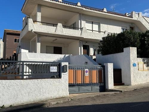 una casa blanca con una valla delante en Casa sul mare Porto Torres III en Porto Torres