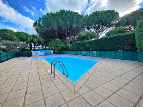- une piscine dans une cour avec des arbres et une clôture dans l'établissement Joli studio à la Grande Motte, à La Grande Motte