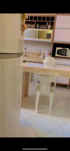 eine Küche mit einem Tisch und einem weißen Stuhl in der Unterkunft Casa da Tati in Cayru