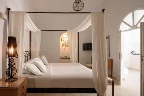 a bedroom with a white bed with a canopy at Kamares Apartments in Fira
