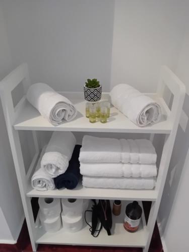 - une étagère blanche avec des serviettes et d'autres serviettes dans l'établissement PERLA PREMIUM APARTMENT, à Timişoara