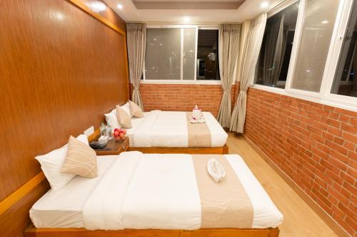 two beds in a room with a brick wall at Paradise Boutique Hotel in Pokhara