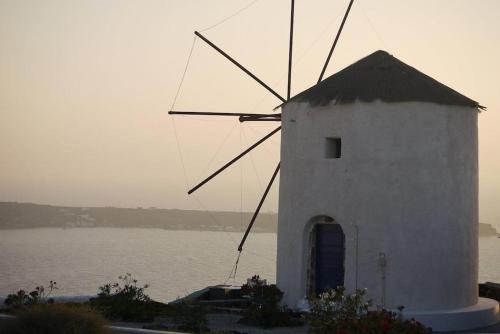 a windmill sitting next to a body of water at Lioyerma Windmill Villa With Outdoor Hot Tub in Oia