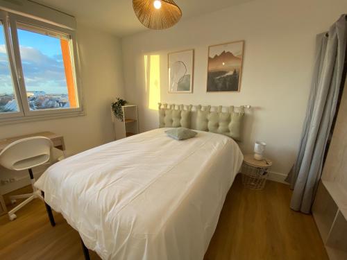 a bedroom with a white bed and a window at Appartement 3 chambres travail et détente à Laval in Laval