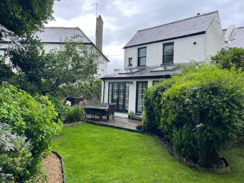 a white house with a garden and a lawn at Lovely Charmouth cottage with log fire & garden close to beach in Charmouth