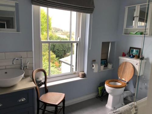 baño con aseo y lavabo y ventana en Lovely Charmouth cottage with log fire & garden close to beach, en Charmouth