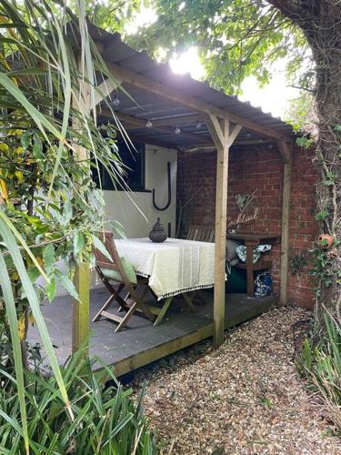a wooden pergola with a bed on a patio at Lovely Charmouth cottage with log fire & garden close to beach in Charmouth