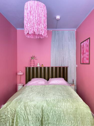 a pink bedroom with a bed and a chandelier at Värikäs koti lähellä keskustaa in Helsinki