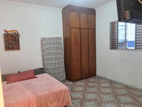 a bedroom with a bed and a wooden cabinet at Apto boqueirão Praia Grande 800 MTS Praia in Praia Grande
