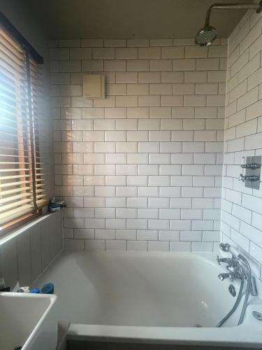 a white bath tub in a bathroom with a window at Sunny Room in Highbury in London