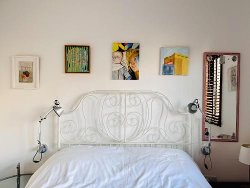 a white bed in a bedroom with pictures on the wall at Sunny Room in Highbury in London