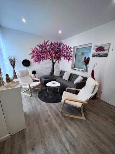 a living room with a black couch and a tree at Ferienwohnung zwischen Wald und Wasser in Berlin