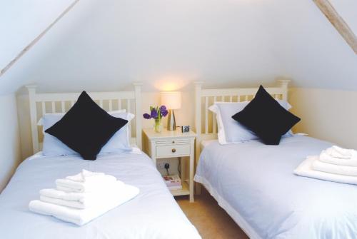 two beds in a room with white sheets and black pillows at Luxury barn with tennis court in South Downs National Park in Chichester