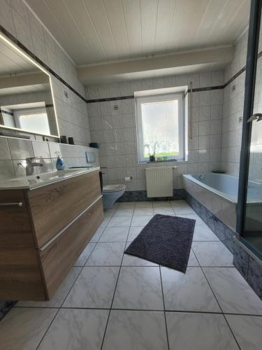 a bathroom with a tub and a sink and a toilet at Ahrtal Vier Sterne Ferienwohnungen Alexandra Weiler Panorama in Bad Neuenahr-Ahrweiler