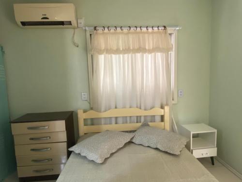 een slaapkamer met een bed, een dressoir en een raam bij Casa Praia Perola in Passo de Torres