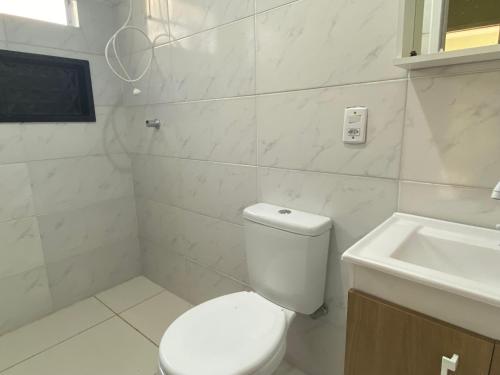een witte badkamer met een toilet en een wastafel bij Casa Praia Perola in Passo de Torres