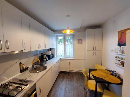 a kitchen with white cabinets and a sink and a table at Sunflower apt in Timişoara