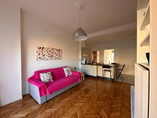 un soggiorno con divano rosa e una cucina di Kibilù - Via Lomellina MM Argonne - Linate Airport a Milano
