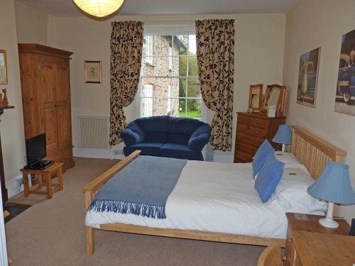 a bedroom with a bed and a chair and a window at Town Mills in Dulverton