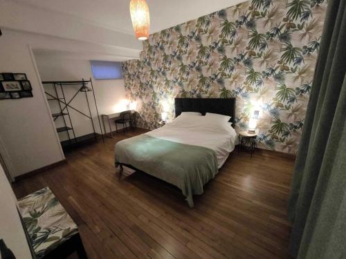 a bedroom with a large bed with a floral wall at Atelier des Rêves in Aulnoye-Aymeries