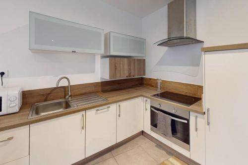 a kitchen with white cabinets and a sink at Marechal Joffre - RDC - Grand F2 in Le Havre