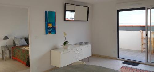 Cette chambre blanche comprend un lit et une commode blanche. dans l'établissement Harbour View Apartment, à Marseillan