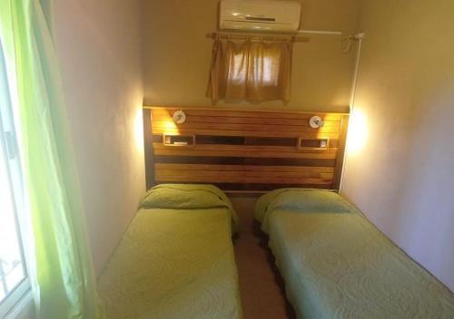 2 camas en una habitación pequeña con ventana en Bungalows El Zarateno en Colón