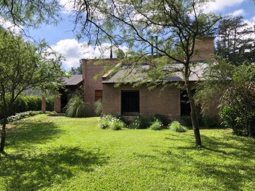 ein altes Backsteinhaus mit einem Rasenhof in der Unterkunft Casa en Sierras de Córdoba, Villa la Bolsa. in La Bolsa