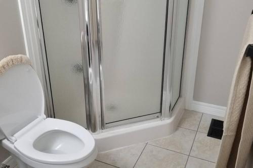 uma casa de banho com um chuveiro e um WC branco em Cozy Luxurious Detached 4 Bedroom House em Guelph