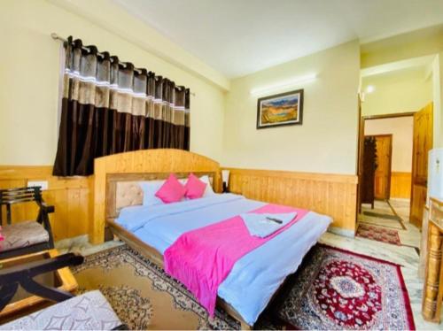 a bedroom with a large bed with a pink blanket at hotel jupiter tamilnadu in Ooty