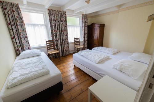 2 camas en una habitación con 2 sillas y una ventana en Herenhuis de Pastorie Groede, en Groede