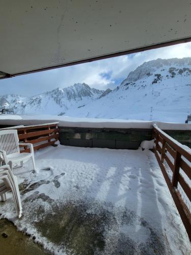 a snowy balcony with a bench and snow covered mountains at Appartements pied des pistes - Résidence Mongie - Tourmalet in La Mongie