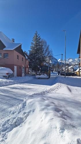 a street covered in snow with a building and a tree at Apartman A&J in Žabljak