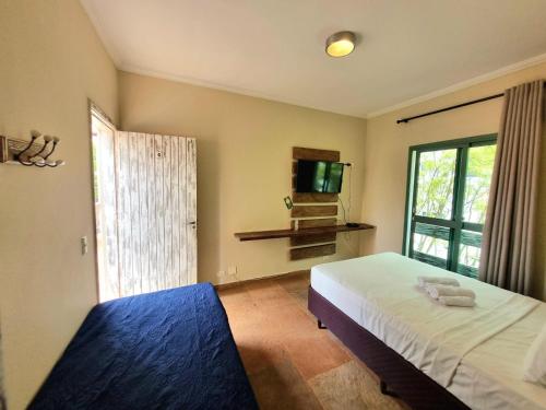 a bedroom with a bed and a tv and a window at Vila Jabutis in Guarujá