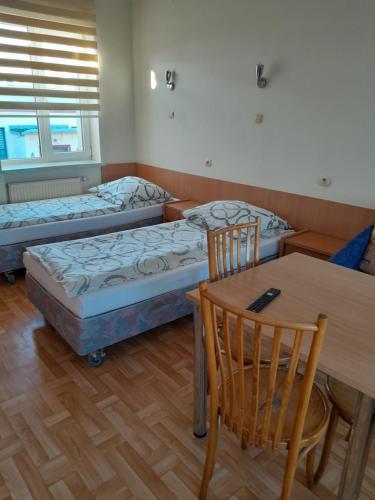 2 camas en una habitación con mesa y sillas en Hostel Polon, en Pułtusk