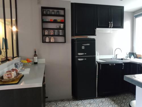 - une cuisine avec des armoires noires et un réfrigérateur noir dans l'établissement Paris Bécon, à Asnières-sur-Seine