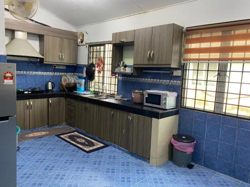 uma cozinha com armários de madeira e piso em azulejo azul em Nilai Bronizam Homestay em Nilai
