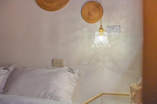 a bedroom with a white bed with a light on the wall at Zhu Shan Xian Ting in Jincheng