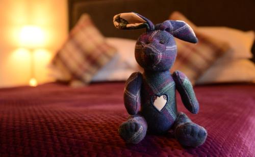 a small teddy bear sitting on a bed at Lochview House in Fort William