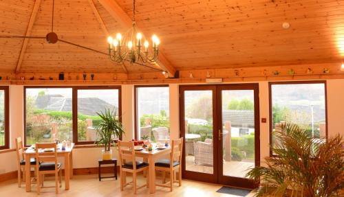 a dining room with a table and chairs and windows at Lochview House in Fort William