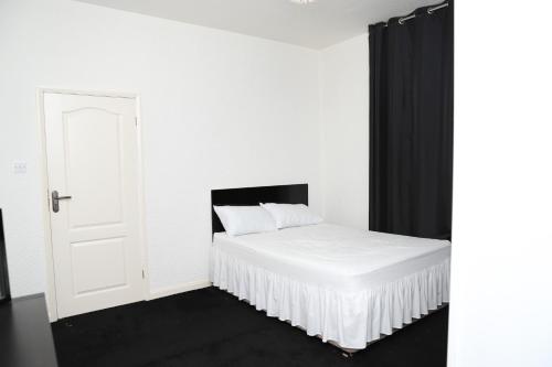 een wit bed in een witte kamer met een deur bij Beautiful and spacious 4- bedroom house in Sunderland in Pallion