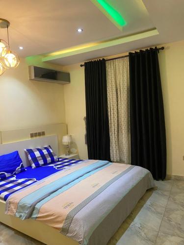 a bedroom with a large bed with black curtains at Zurik Apartments in Kusafe