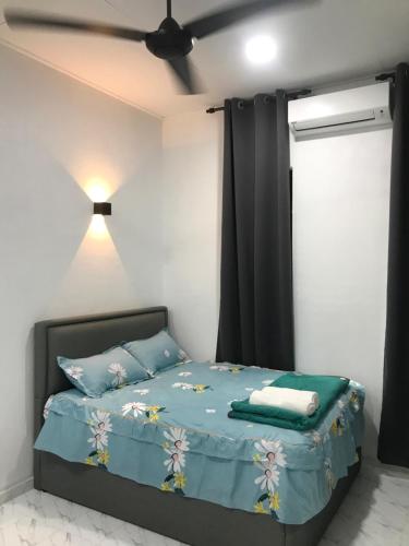 a bedroom with a bed with blue sheets and a ceiling fan at AINUL HOMESTAY in Pasir Mas