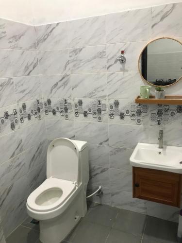La salle de bains est pourvue de toilettes blanches et d'un lavabo. dans l'établissement AINUL HOMESTAY, à Pasir Mas