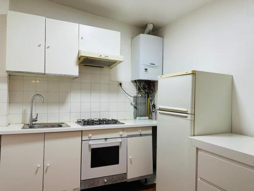 uma cozinha com armários brancos e um frigorífico em Modern & Comfortable City Center Oasis~King Bed ! em Bruxelas