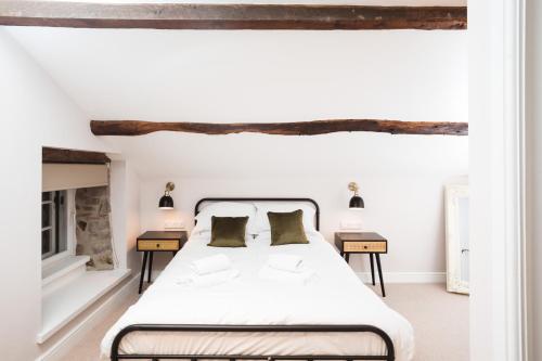 a white bedroom with a bed and two tables at Bankers Room + Kitchenette in Chapel en le Frith