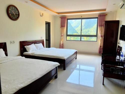a bedroom with two beds and a clock on the wall at Khách sạn So Oanh gần thác Bản giốc in Cao Bằng