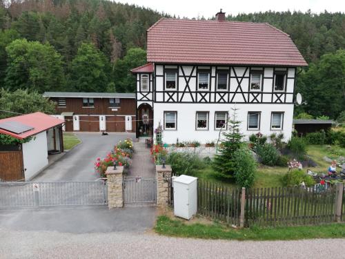 een wit huis met een rood dak en een hek bij Fewo an der Klosterruine Paulinzella mit kostenfreien Parkplatz und WLAN in Königsee