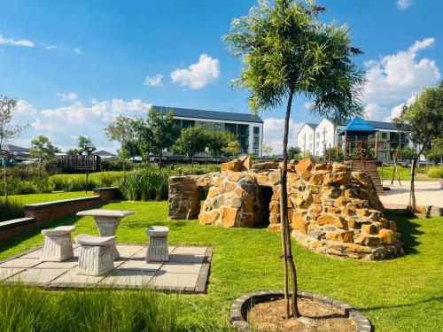 a tree in a park with benches and a rock wall at Lethabo Eco_Estate in Boksburg