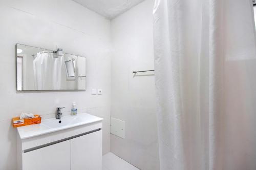 a white bathroom with a sink and a mirror at Quinta Moinhos da Tapada in Luso